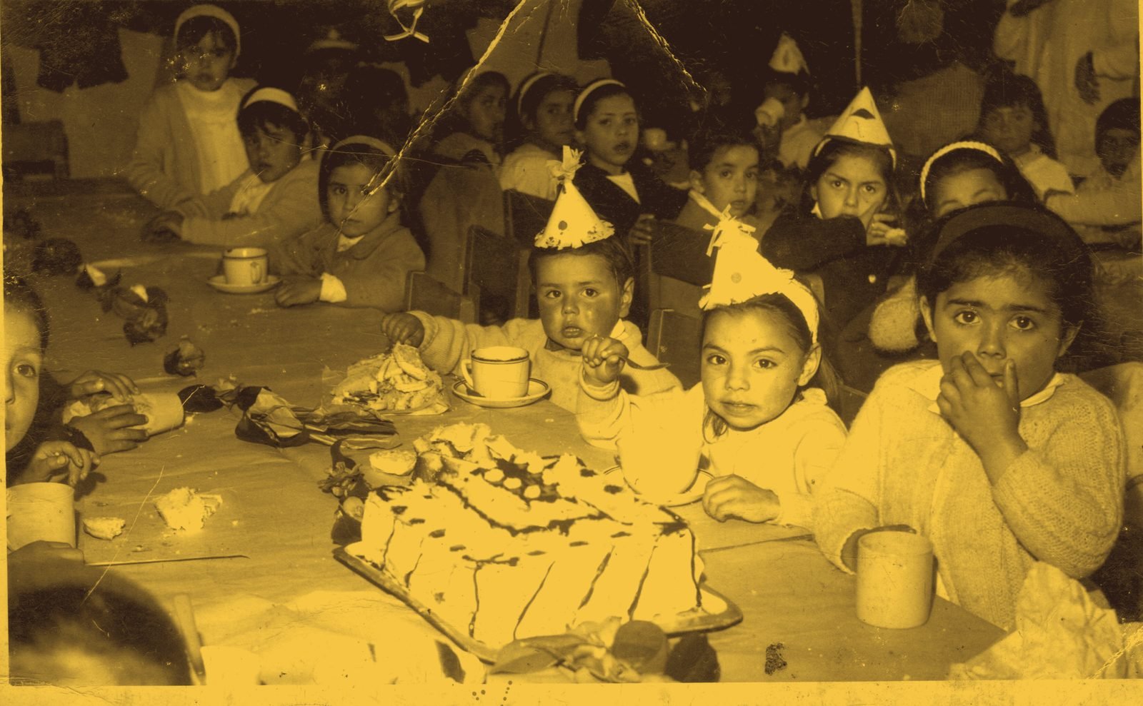 Cumpleaños infantil con torta y gorros de papel, fotografía de archivo familiar